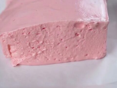 A thick, airy slice of pink strawberry fluff cake on a white square plate.