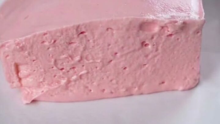 A thick, airy slice of pink strawberry fluff cake on a white square plate.