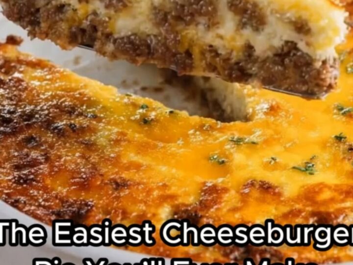 A thick, steaming slice of golden-brown cheeseburger pie being lifted from a white ceramic baking dish.
