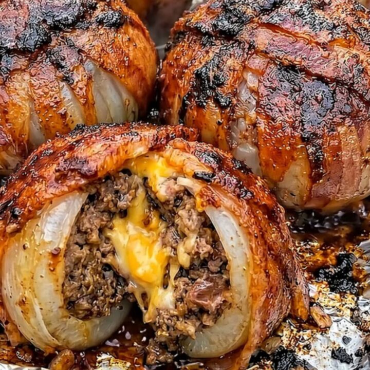 A close-up of a bacon-wrapped stuffed onion sliced in half, revealing the juicy beef and molten cheddar center.