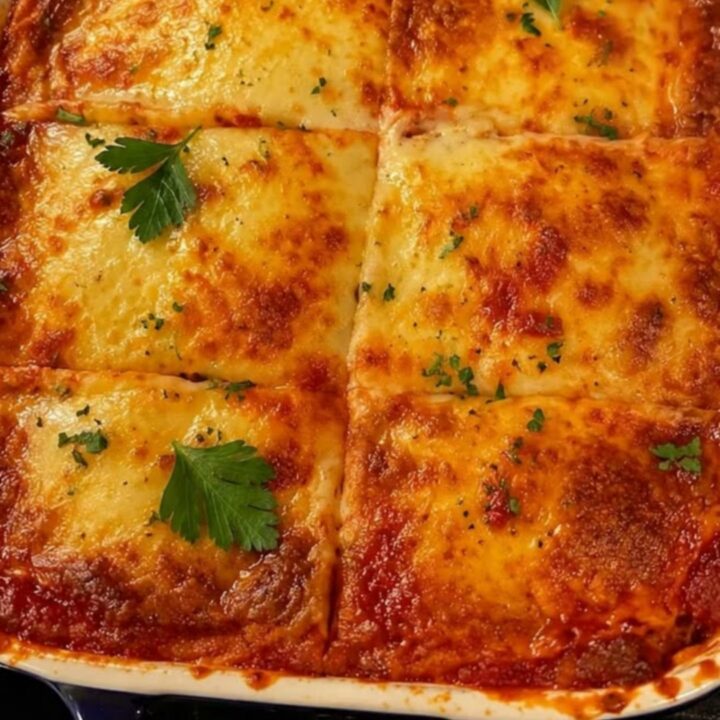 A steaming, freshly baked lasagna in a blue casserole dish with a dramatic cheese pull.
