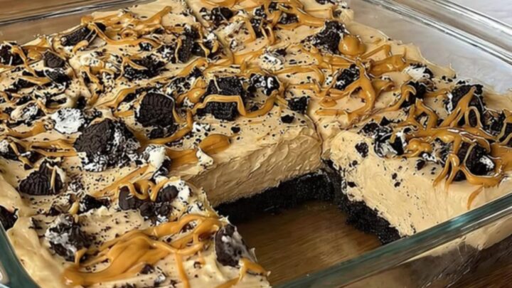 A slice of no-bake peanut butter Oreo pie on a white plate with a dense cookie crust and fluffy peanut butter filling.
