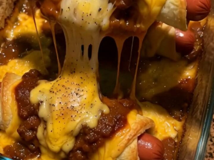 A close-up of a cheesy chili dog crescent roll showing a long, gooey cheese stretch.