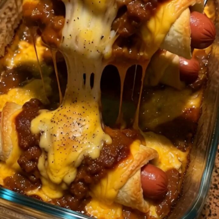 A close-up of a cheesy chili dog crescent roll showing a long, gooey cheese stretch.