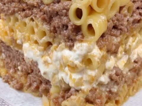 A tall, beautiful slice of golden-brown pastitsio on a decorative plate showing distinct layers.