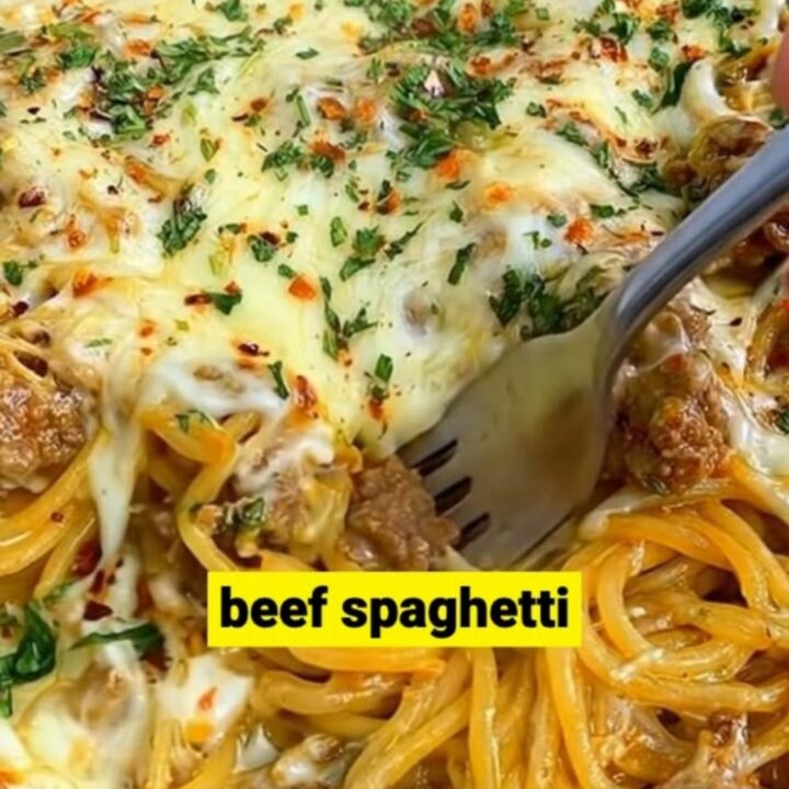 A cast iron skillet filled with creamy Cajun beef spaghetti topped with melted mozzarella, red pepper flakes, and parsley.