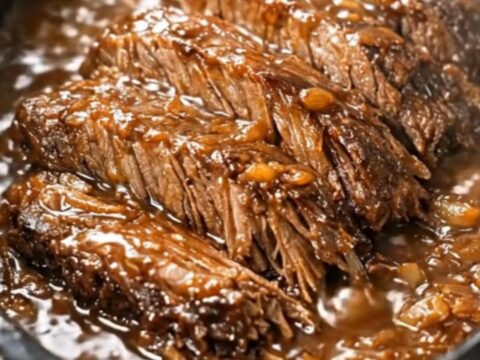 Succulent slow-cooked beef brisket chunks coated in a rich, dark onion gravy in a slow cooker.