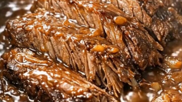 Succulent slow-cooked beef brisket chunks coated in a rich, dark onion gravy in a slow cooker.