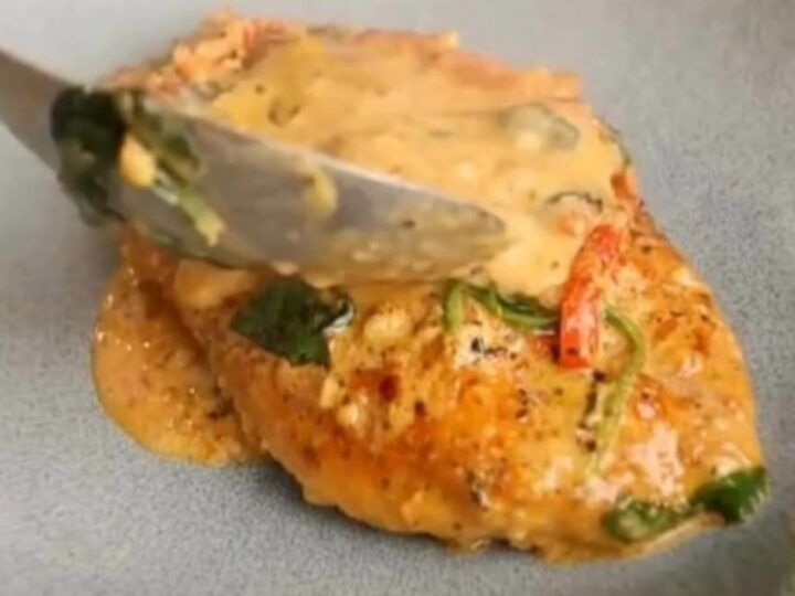 A rustic grey bowl filled with golden-seared chicken breast smothered in a creamy sun-dried tomato and spinach sauce.