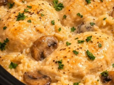 A close-up of creamy mushroom chicken and rice in a slow cooker, garnished with fresh parsley.