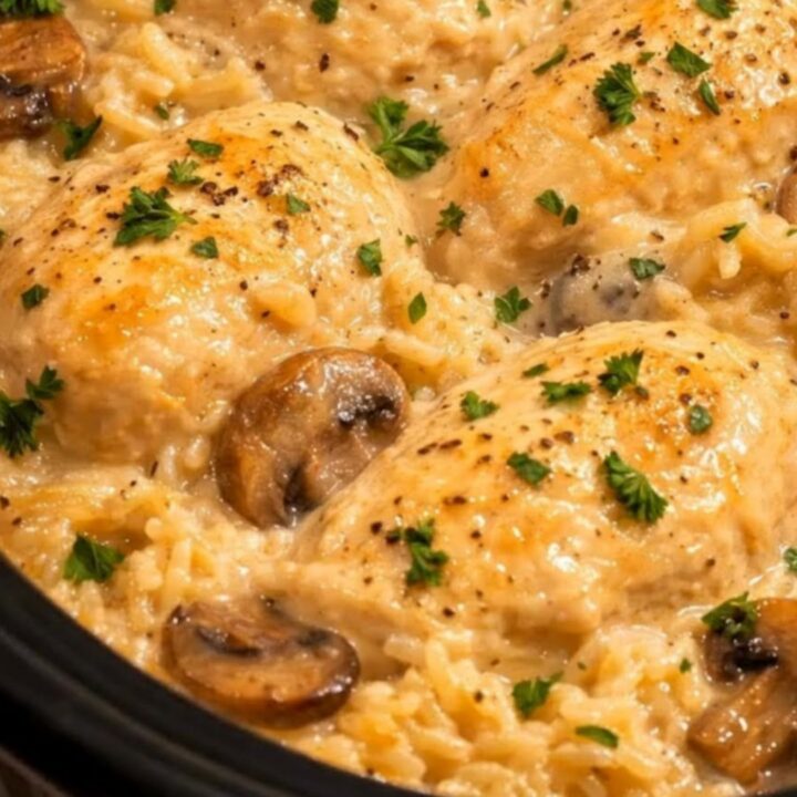 A close-up of creamy mushroom chicken and rice in a slow cooker, garnished with fresh parsley.