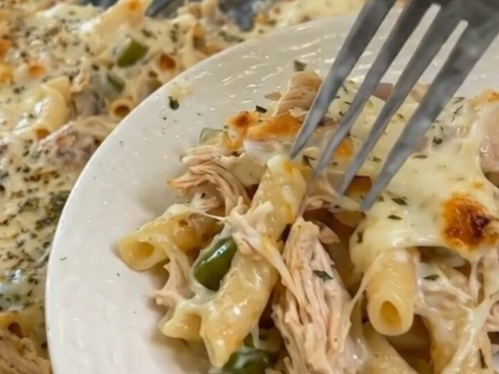 A fresh portion of Mississippi chicken casserole served on a white plate next to the baking dish.
