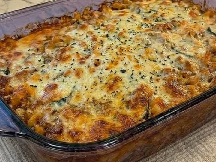 A bubbly, golden-brown cheese crust baked on a large glass casserole dish filled with rich pasta.