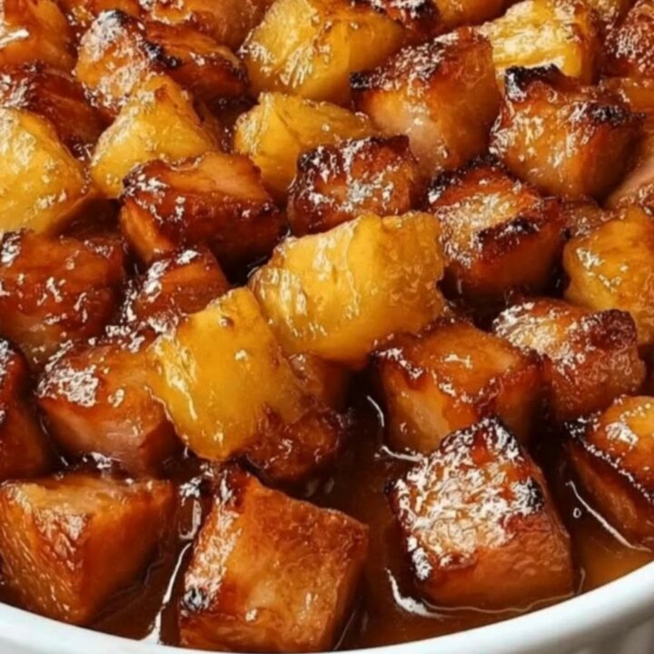 Bouchées de jambon et ananas caramélisées, luisantes sous une lumière chaude et dorée.