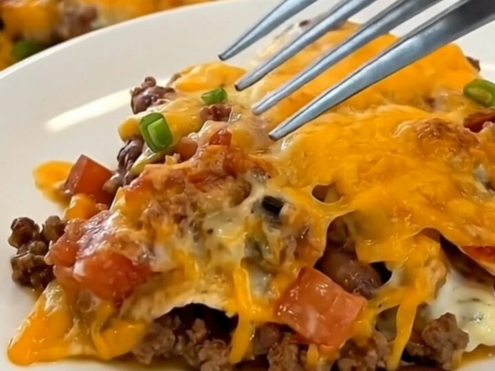 A plated serving of cheesy firecracker casserole showing layers of seasoned beef, beans