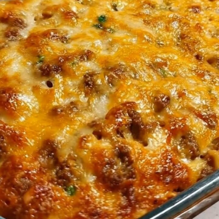 A steaming slice of million dollar cheesy beef spaghetti being lifted from a glass casserole dish with stretching melted