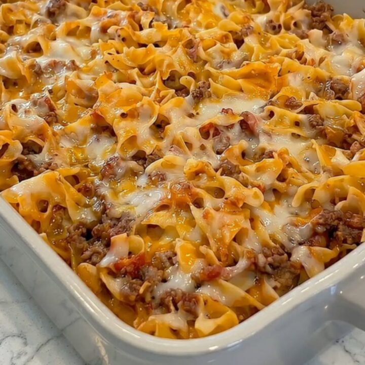 A steamy portion of cheesy ground beef noodle casserole being lifted with a spatula