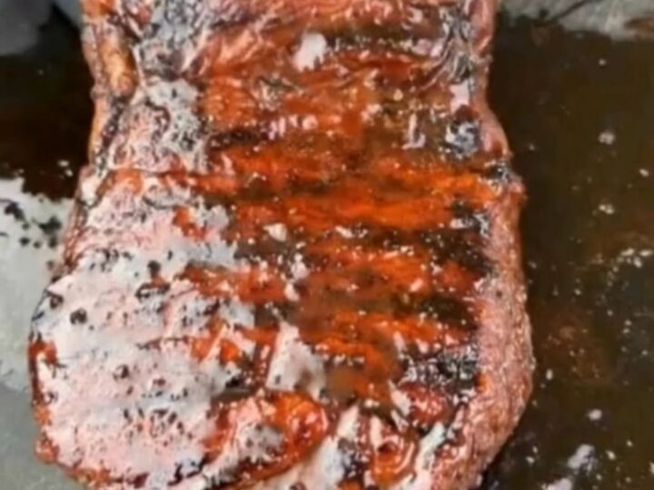 A perfectly grilled ribeye steak with a glossy, charred glaze sitting on a wooden board.