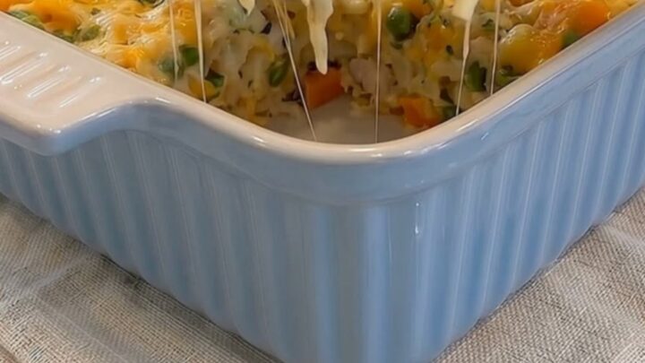 A serving spoon lifting a hot scoop of cheesy chicken hash brown casserole with a long cheese stretch