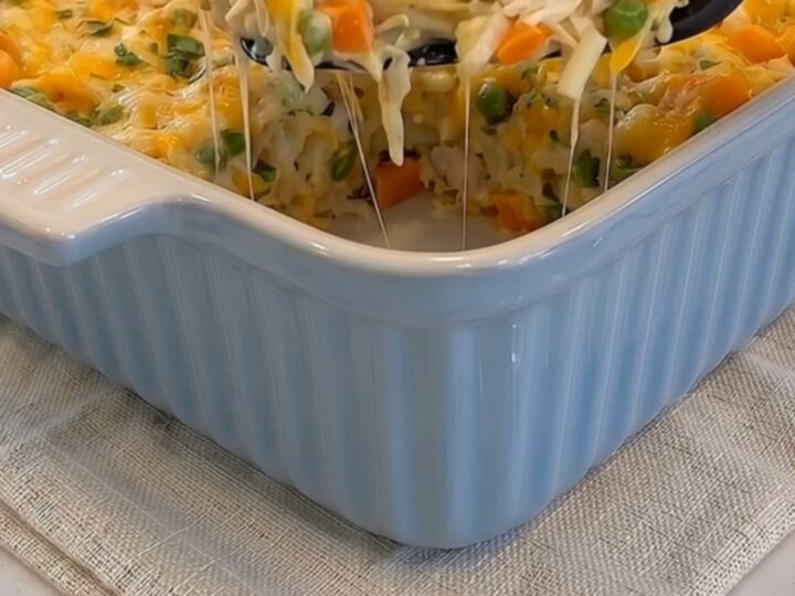 A serving spoon lifting a hot scoop of cheesy chicken hash brown casserole with a long cheese stretch