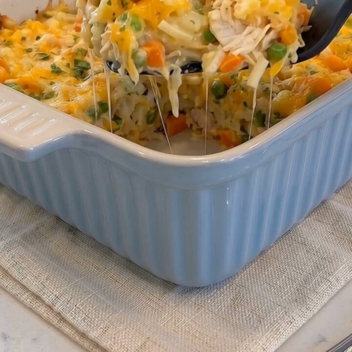 A serving spoon lifting a hot scoop of cheesy chicken hash brown casserole with a long cheese stretch