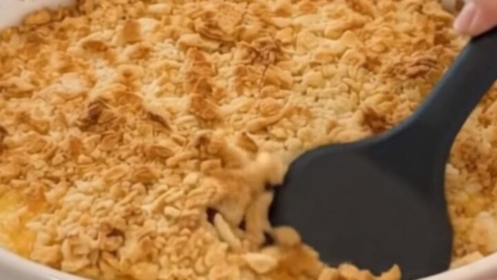 A close-up of a creamy chicken casserole in a white fluted dish with a golden cracker crust.