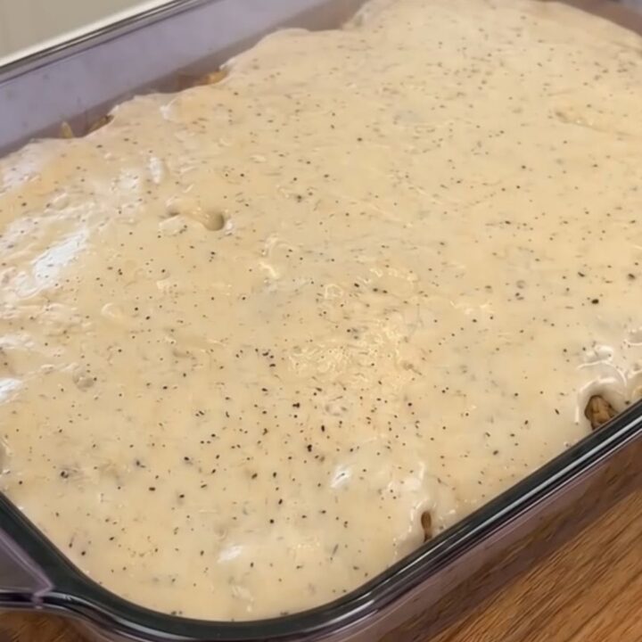 Gratin de pommes de terre rissolées, bacon et cheddar fondu dans un plat en verre.