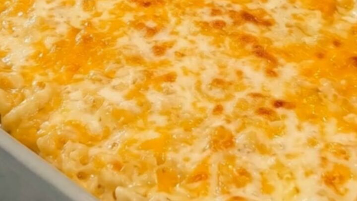 A steaming, golden-brown baked mac and cheese in a grey ceramic dish on a marble counter.