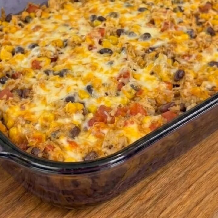 A close-up of a serving spoon pulling away a portion of the cheesy chicken casserole, showing melted cheese.