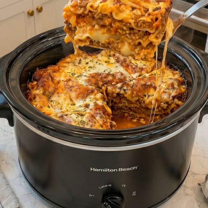 A thick, steaming slice of slow cooker lasagna being lifted with a spatula, showing a long cheese pull.