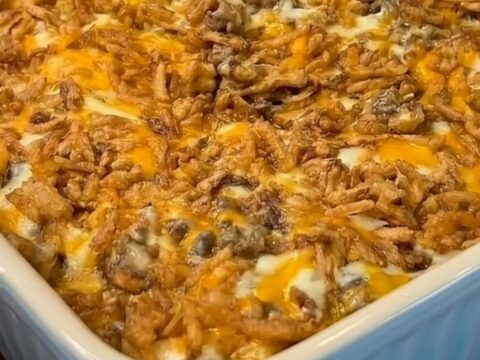 A steaming scoop of cheesy French onion hamburger casserole with an elastic stretch of melted Colby Jack cheese and crispy