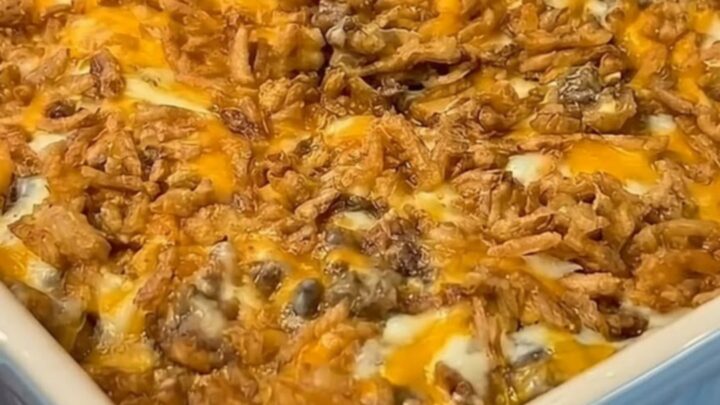 A steaming scoop of cheesy French onion hamburger casserole with an elastic stretch of melted Colby Jack cheese and crispy
