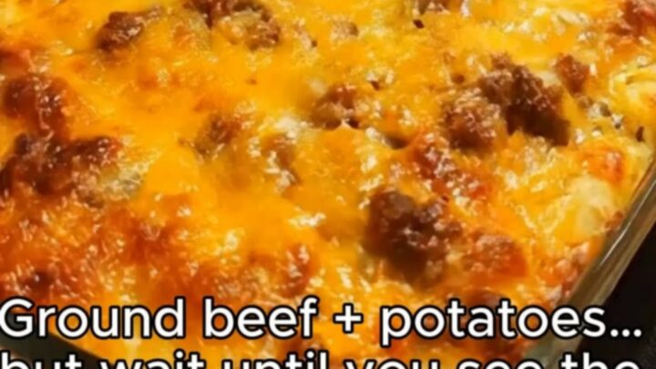 A close-up of a cheesy hamburger and potato casserole with a golden brown melted cheese topping in a glass dish.