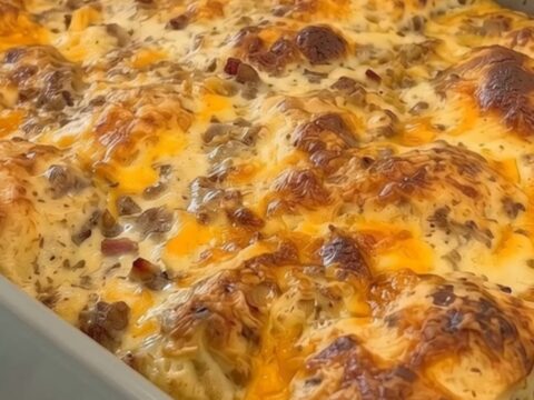 Une casserole de petit-déjeuner dorée avec du fromage fondant dans un plat en céramique.