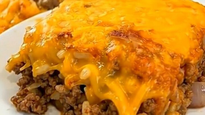 A square portion of Tex-Mex beef and cauliflower casserole on a white plate with melted golden cheese.