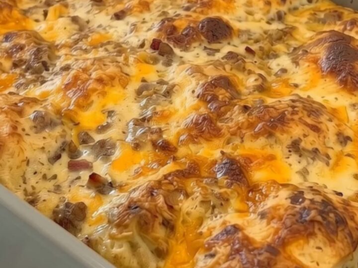 A steaming slice of loaded biscuits and sausage gravy breakfast casserole being lifted with a metal spatula
