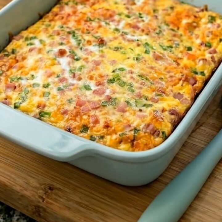 Une casserole de petit-déjeuner dorée avec des œufs, du jambon et du fromage fondu dans un plat bleu.