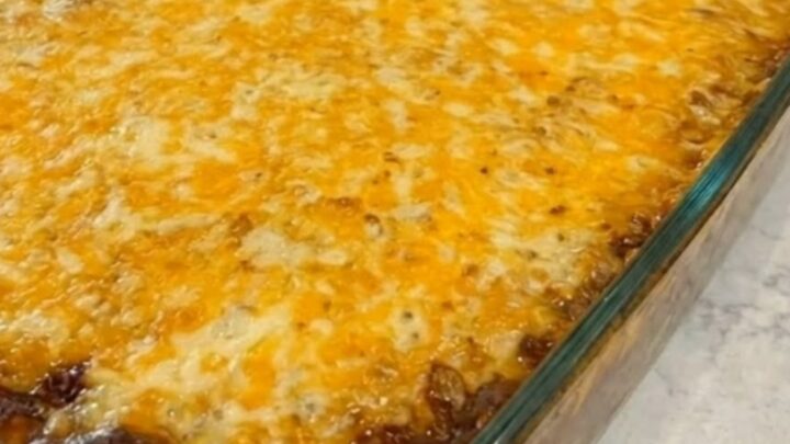 A rectangular glass baking dish filled with golden-brown cornbread casserole, showing melted cheese on top.