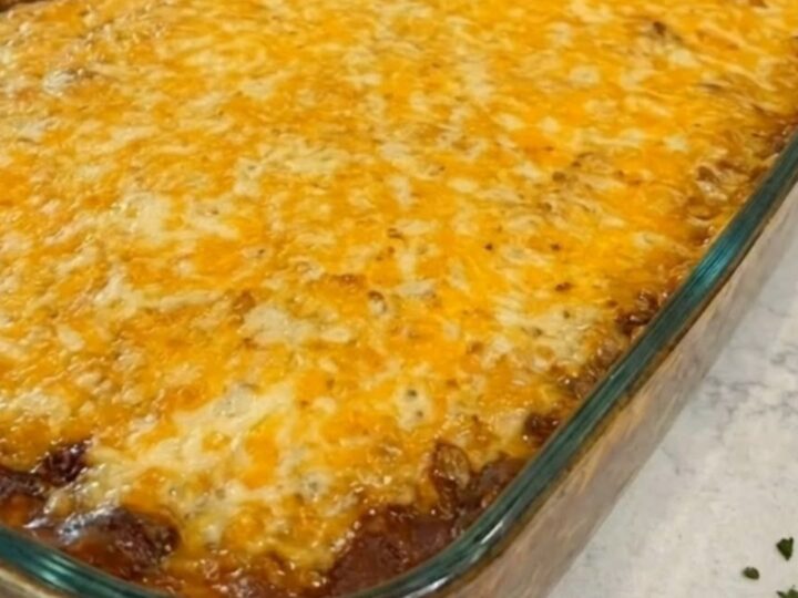 A rectangular glass baking dish filled with golden-brown cornbread casserole, showing melted cheese on top.