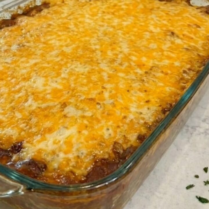 A rectangular glass baking dish filled with golden-brown cornbread casserole, showing melted cheese on top.