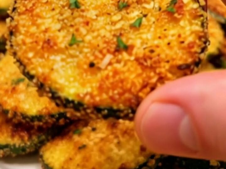 Gros plan sur une chips de courgette au parmesan dorée et croustillante coupée en deux.