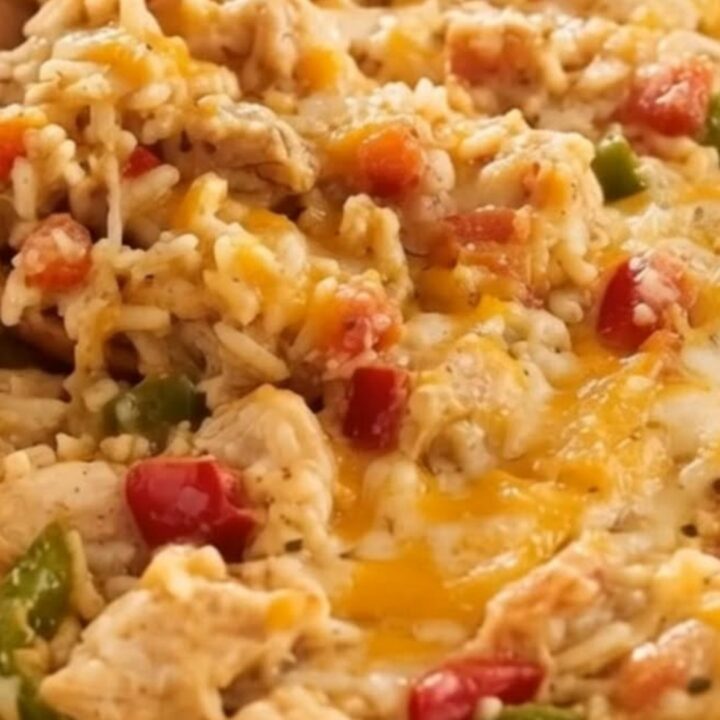 A steaming, freshly baked chicken fajita casserole in a white ceramic dish with melted, stretchy cheese.