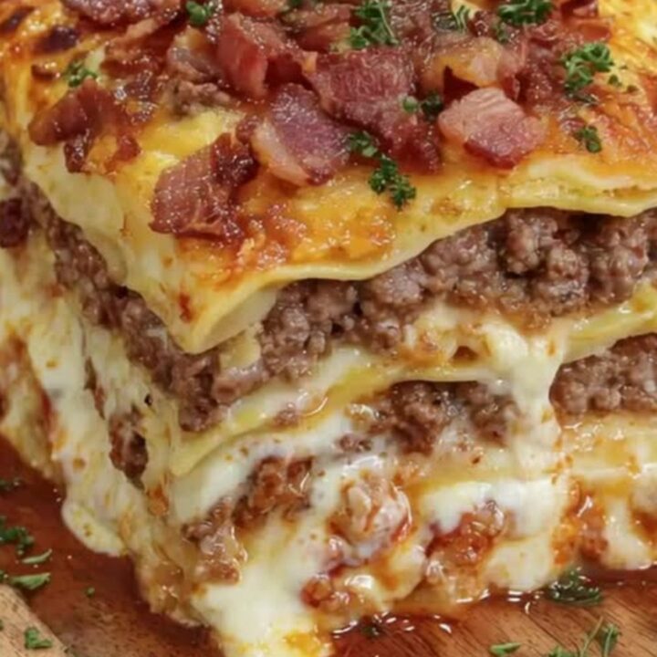 A tall, square slice of bacon cheeseburger lasagna showing distinct meat and pasta layers.