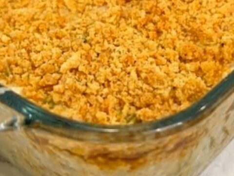 A serving spoon scooping into a golden cracker crust of a rich and creamy chicken casserole