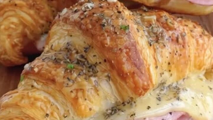 Croissants au jambon et fromage dorés et croustillants sur une planche en bois avec de la vapeur.