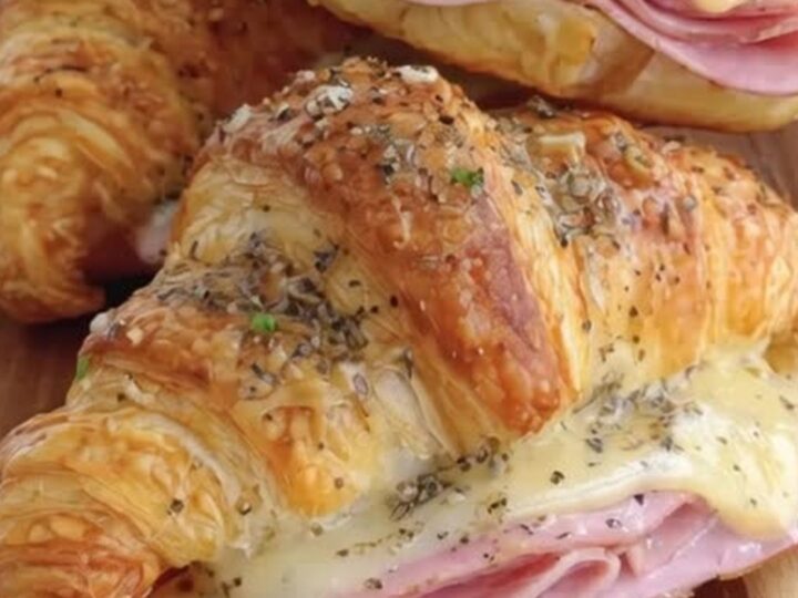 Croissants au jambon et fromage dorés et croustillants sur une planche en bois avec de la vapeur.