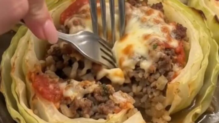 A close-up of baked cabbage rings topped with melted mozzarella and marinara sauce on a metal tray.