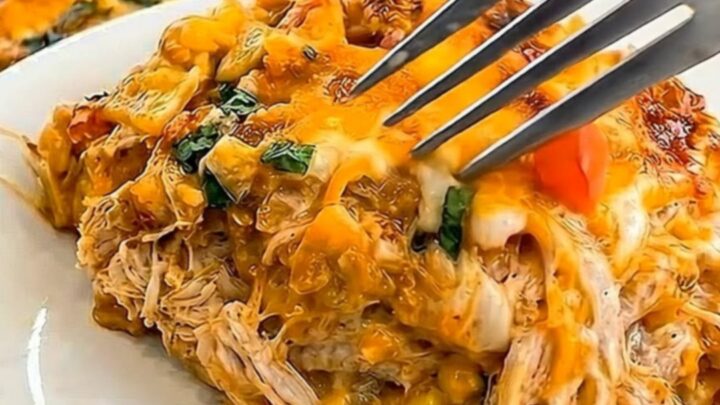 A hearty slice of cheesy King Ranch chicken casserole on a white plate with the baked dish in the background.