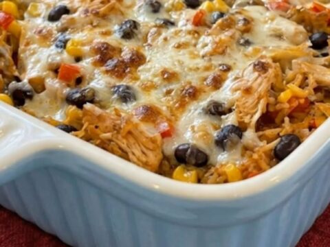 A scoop of bubbling chicken burrito casserole being lifted with a massive, epic melted cheese pull