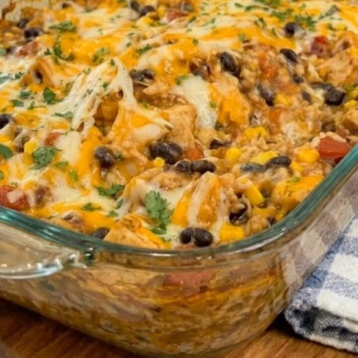 A scoop of cheesy Mexican chicken casserole being lifted from a baking dish, showing a long cheese pull.
